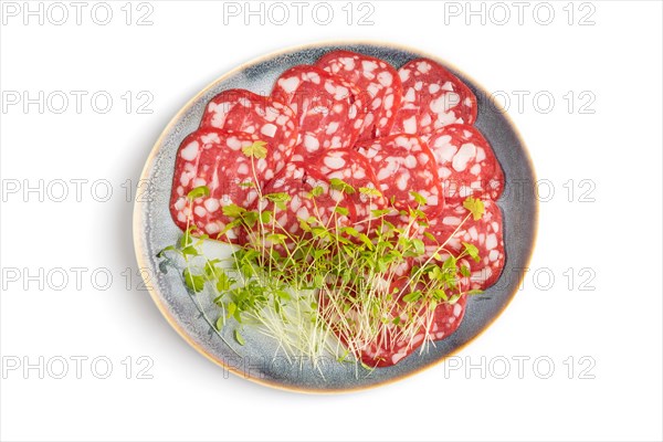 Slices of smoked cervelat salami sausage with spinach microgreen isolated on white background. Top view, flat lay, close up