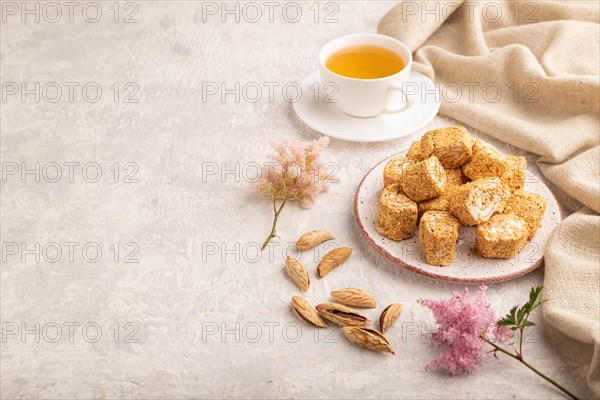 Traditional turkish delight (rahat lokum) with cup of green tea on a gray concrete background and linen textile. side view, copy space