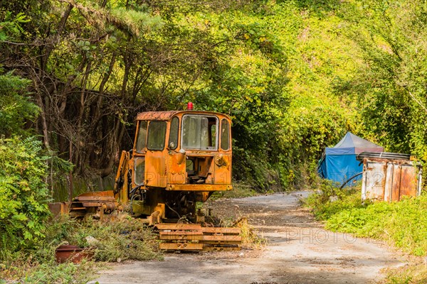 Old, rusted, broken down bulldozer sitting on abandoned unused road in wilderness