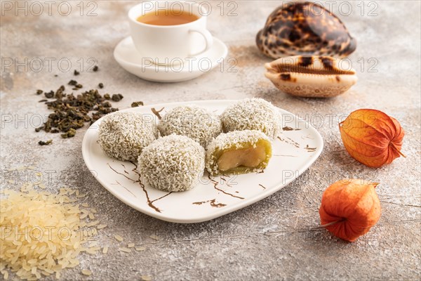 Japanese rice sweet buns mochi filled with pandan jam and cup of green tea on brown concrete background. side view, close up