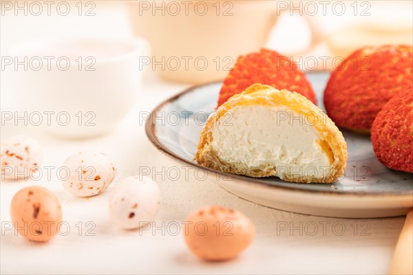 Traditional french custard dessert shu cake and cup of green tea on white wooden background and orange linen textile. side view, close up, selective focus. Breakfast, morning, concept