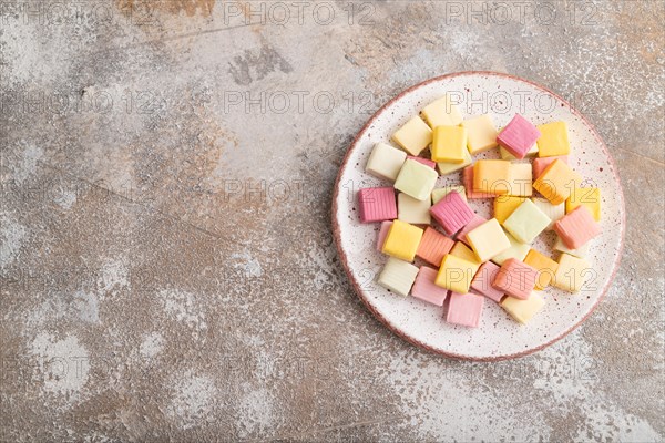 Various fruit jelly chewing candies on plate on brown concrete background. apple, banana, tangerine, top view, flat lay, copy space