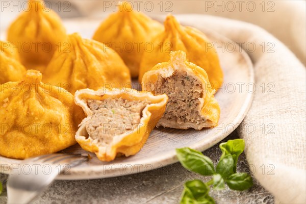 Fried manti dumplings with pepper, basil on gray concrete background and linen textile. Side view, close up, selective focus