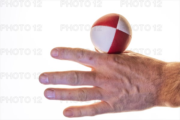 Hand with a juggling ball in front of a white background, studio shot, Germany, Europe