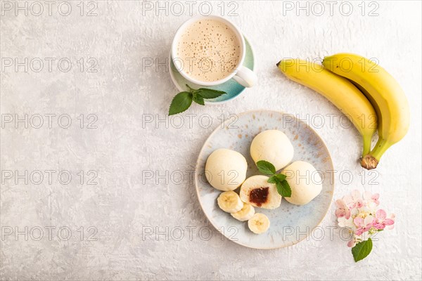 Japanese rice sweet buns mochi filled with jam and cup of coffee on a gray concrete background. top view, flat lay, copy space