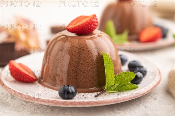 Chocolate jelly with strawberry and blueberry on gray concrete background and linen textile. side view, close up, selective focus