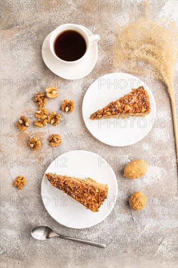 Walnut and hazelnut cake with caramel cream, cup of coffee on brown concrete background. top view, flat lay
