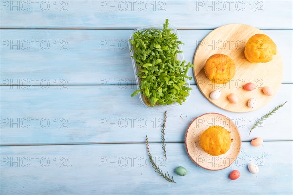Homemade cakes with chocolate eggs and chrysanthemum microgreen on a blue wooden background. top view, flat lay, copy space