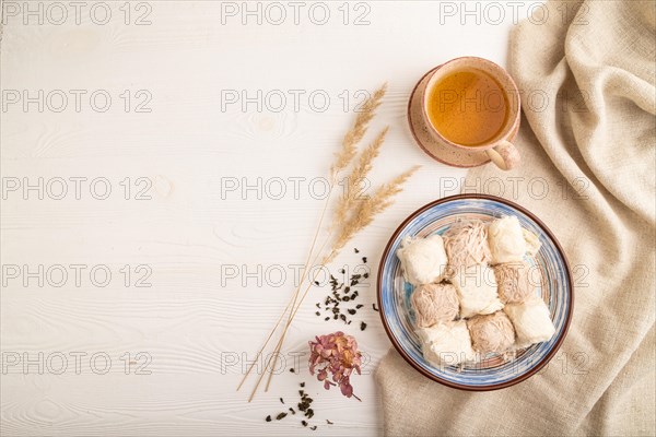 Traditional arabic sweets pishmanie and a cup of green tea on white wooden background and linen textile. top view, flat lay, copy space