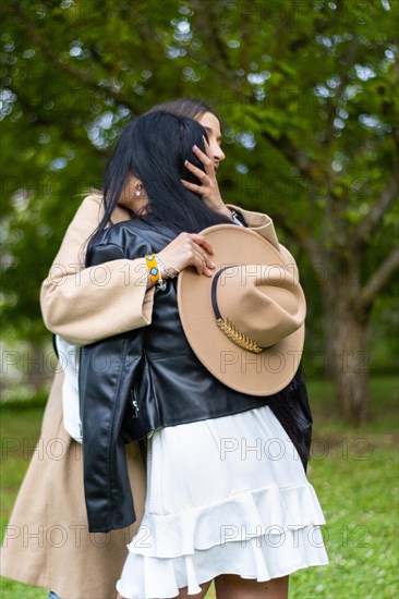 Portrait of two female friends standing hugging on the grass, Rear view of two female friends hugging on the grass. Girls friendship concept