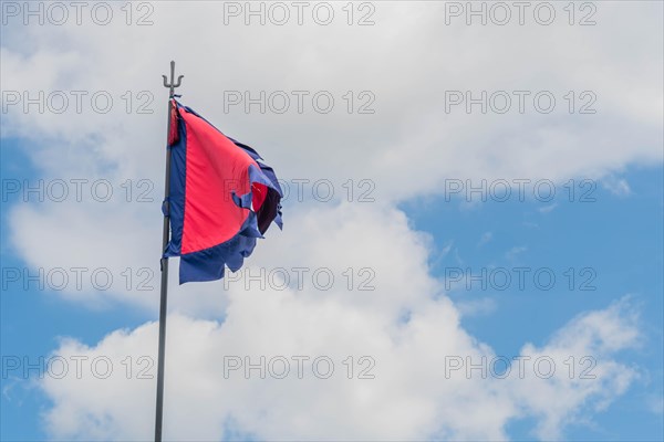 Red flag with blue fringe on metal pole under cloudy blue sky in South Korea