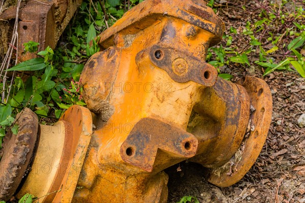 Closeup of broken down bulldozer trans-axle laying in weeds on ground