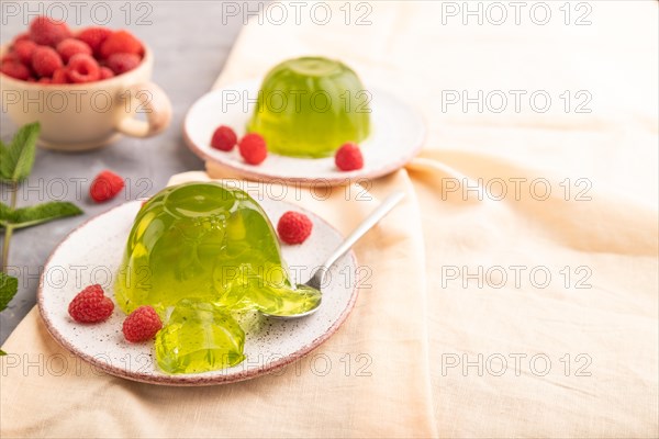 Mint and raspberry green jelly on gray concrete background and orange linen textile. side view, close up, selective focus