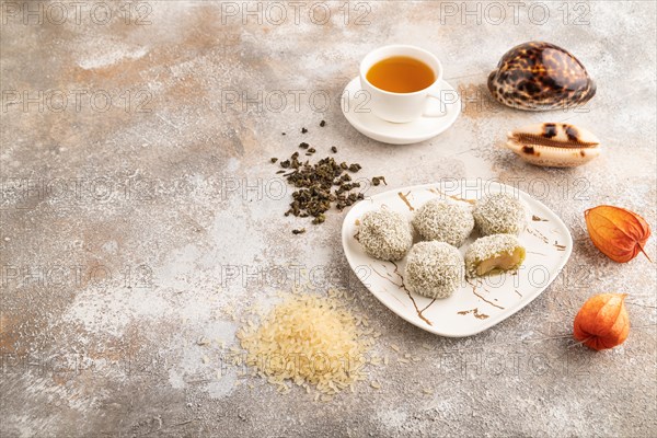 Japanese rice sweet buns mochi filled with pandan jam and cup of green tea on brown concrete background. side view, copy space