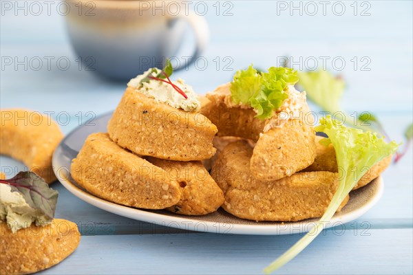 Homemade salted crescent-shaped cheese cookies, cup of coffee on blue wooden background. side view, selective focus