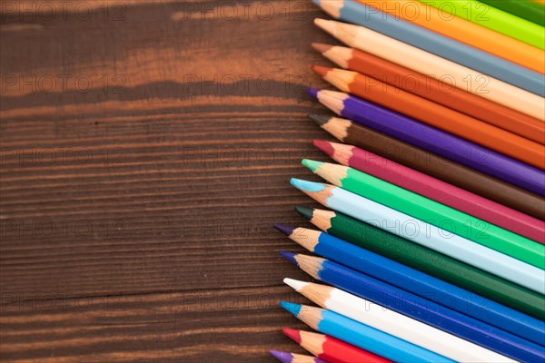 Set of watercolor pencils on brown wooden background. Top view, flat lay, copy space