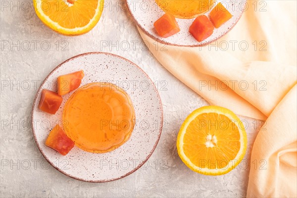 Papaya and orange jelly on gray concrete background and orange linen textile. top view, flat lay, close up