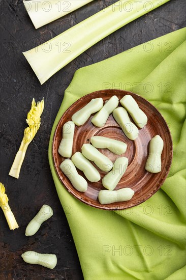 Jelly celery candies on black concrete background and green linen textile. close up, top view, flat lay