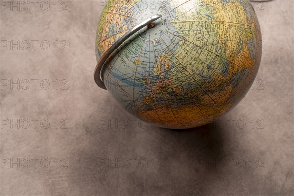 An old-fashioned globe on a grey texture with focus on the northern hemisphere, studio shot, top view, Germany, Europe