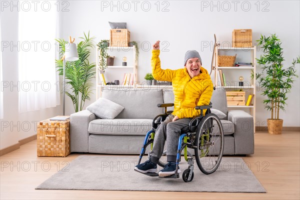 Portrait with copy space of a disabled man in wheelchair celebrating raising fist at home