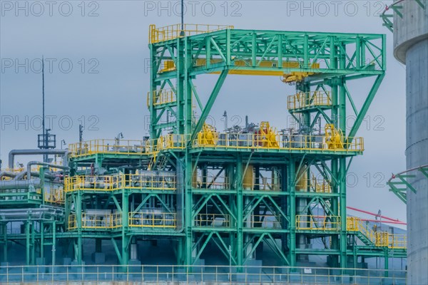 Closeup of upper portion of worker platform next to and on top of gasoline storage tank on a cloudy overcast day