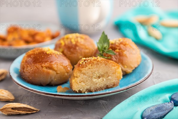 Homemade traditional turkish dessert sekerpare with almonds and honey, cup of green tea on gray concrete background and blue textile. side view, selective focus