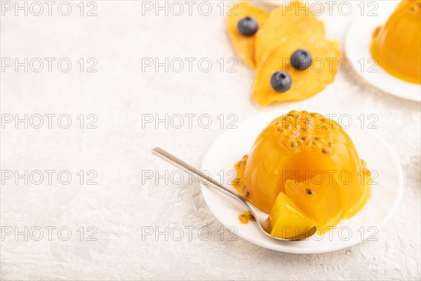 Mango and passion fruit jelly with blueberry on gray concrete background and linen textile. side view, copy space