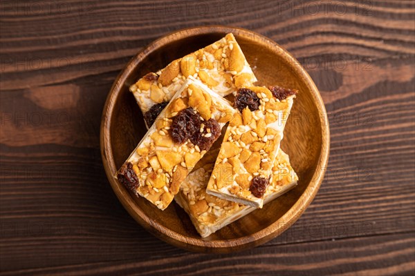 Traditional candy nougat with nuts and sesame on brown wooden background. top view, flat lay, close up