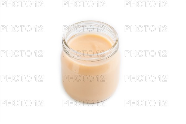 Baby puree with fruits mix, apple, banana infant formula in glass jar isolated on white background. Side view, close up, artificial feeding concept