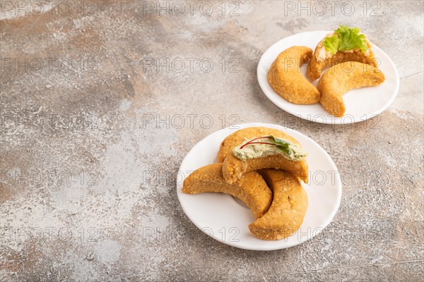 Homemade salted crescent-shaped cheese cookies on brown concrete background. side view, copy space