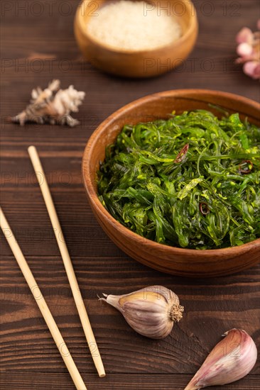 Chuka seaweed salad in wooden bowl on brown wooden background. Side view, close up, selective focus