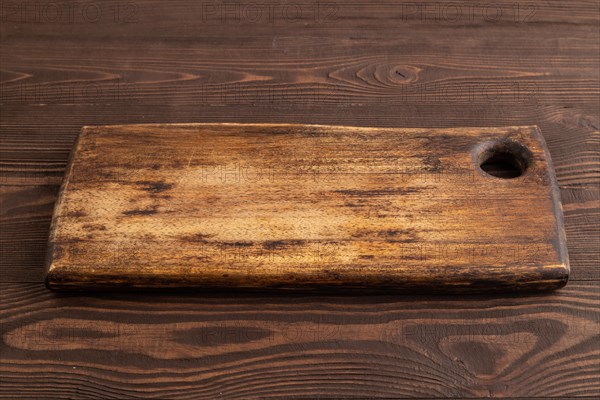 Empty rectangular wooden cutting board on brown wooden background. Side view, close up