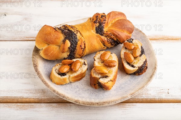 Homemade sweet bun with honey almonds on a white wooden background. side view, close up