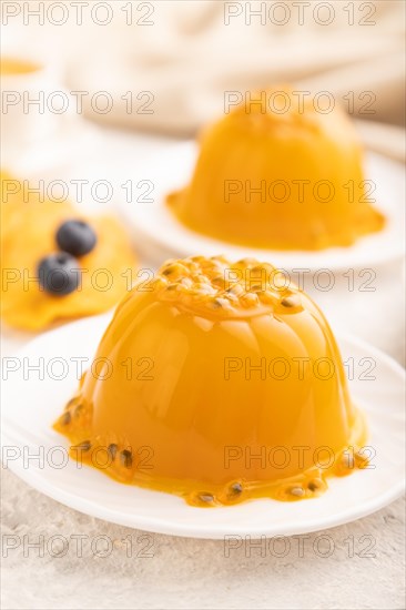 Mango and passion fruit jelly with blueberry on gray concrete background and linen textile. side view, close up, selective focus