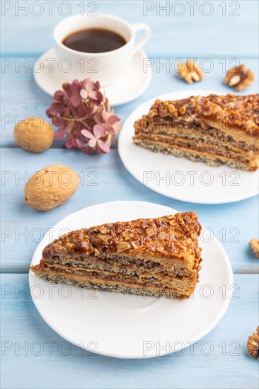 Walnut and hazelnut cake with caramel cream, cup of coffee on blue wooden background. side view, copy space
