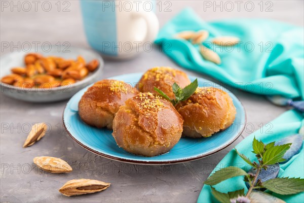 Homemade traditional turkish dessert sekerpare with almonds and honey, cup of green tea on gray concrete background and blue textile. side view, selective focus