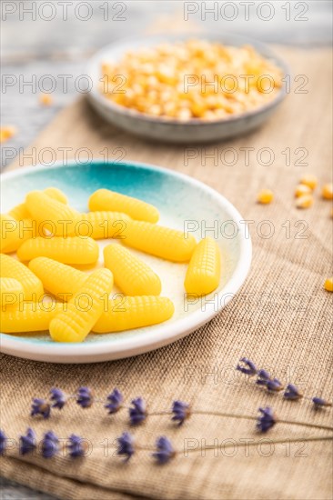 Jelly corn candies on gray wooden background and linen textile. close up, side view, selective focus