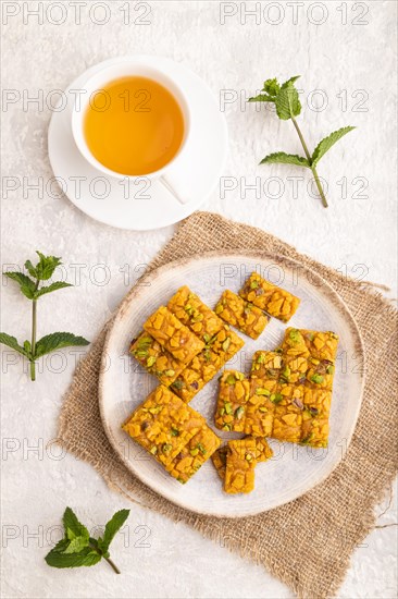 Traditional iranian dessert sohan with cup of green tea on a gray concrete background and linen textile. top view, flat lay, close up