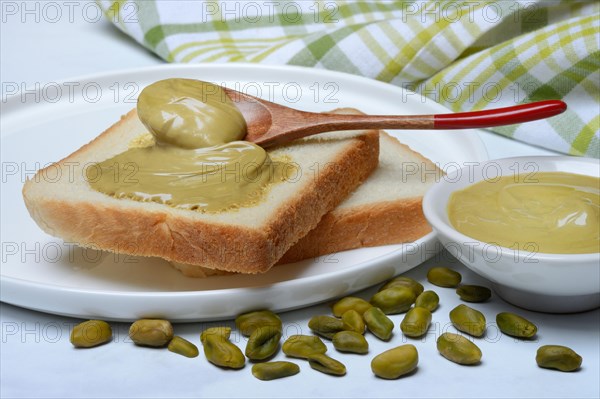 Pistachio cream with spoon on slices of bread, pistachio