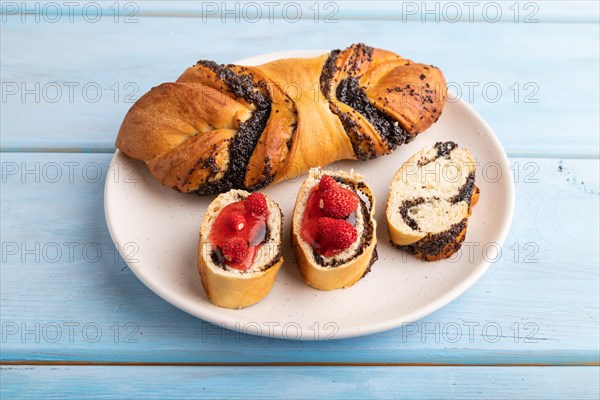 Homemade sweet bun with strawberry jam on a blue wooden background. side view, close up