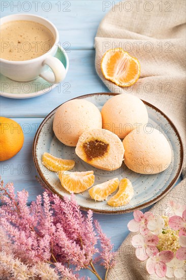 Japanese rice sweet buns mochi filled with tangerine jam and cup of coffee on a blue wooden background and linen textile. side view, close up