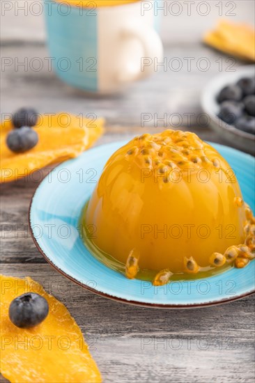Mango and passion fruit jelly with blueberry on gray wooden background. side view, close up, selective focus