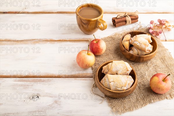 Homemade sweet cookie with apple jam and cup of coffee on white wooden background and linen textile. side view, copy space