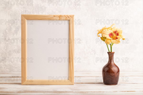 Wooden frame with orange day-lily flowers in ceramic vase on gray concrete background. side view, copy space, still life, mockup, template, spring, summer concept