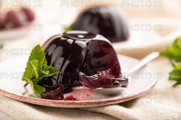 Black currant and grapes jelly on white wooden background and linen textile. side view, close up, selective focus