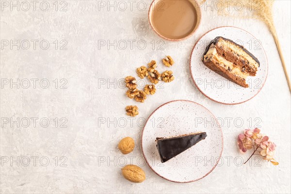 Chocolate biscuit cake with caramel cream and walnuts, cup of coffee on gray concrete background. top view, flat lay, copy space