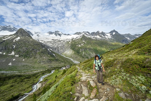 Mountaineer on hiking trail in picturesque mountain landscape, mountain peak with snow and glacier Hornkees and Waxeggkees, summit Grosser Moeseler and mountain hut Berliner Huette, Berliner Hoehenweg, Zillertal Alps, Tyrol, Austria, Europe