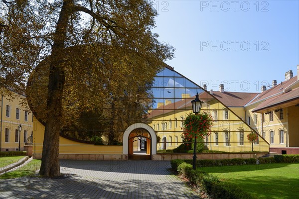 A facade combining historical architecture and modern glass structures in a paved courtyard, church, officers' palace, Komarno, Komarom, Komorn, Nitriansky kraj, Slovakia, Europe