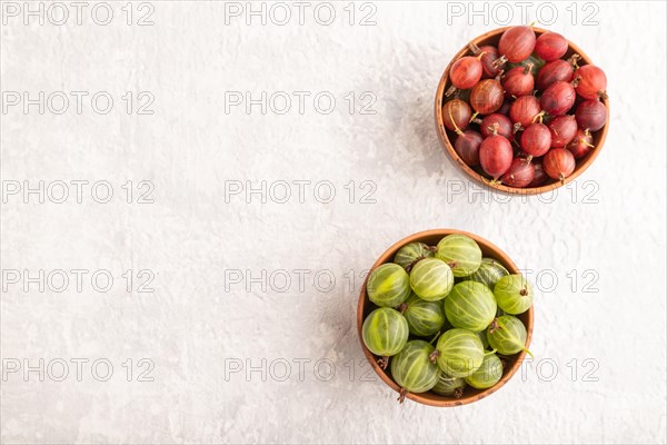 Fresh red and green gooseberry in clay bowl on gray concrete background. top view, flat lay, copy space