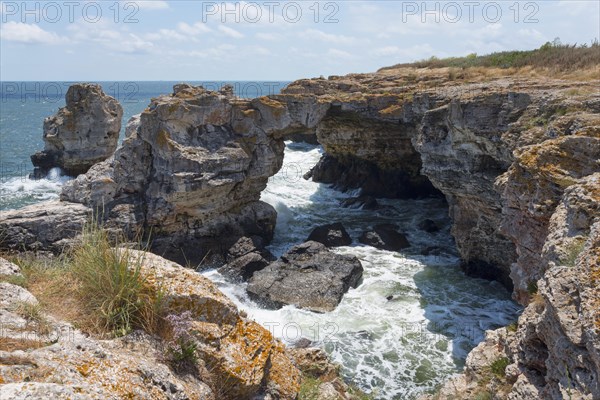 Rugged rock formations and natural arch on a stormy coast against a bright blue sky, rock arch, stone arch, Tyulenovo, Tyulenovo, Shabla, Dobrich, Black Sea, Bulgaria, Europe